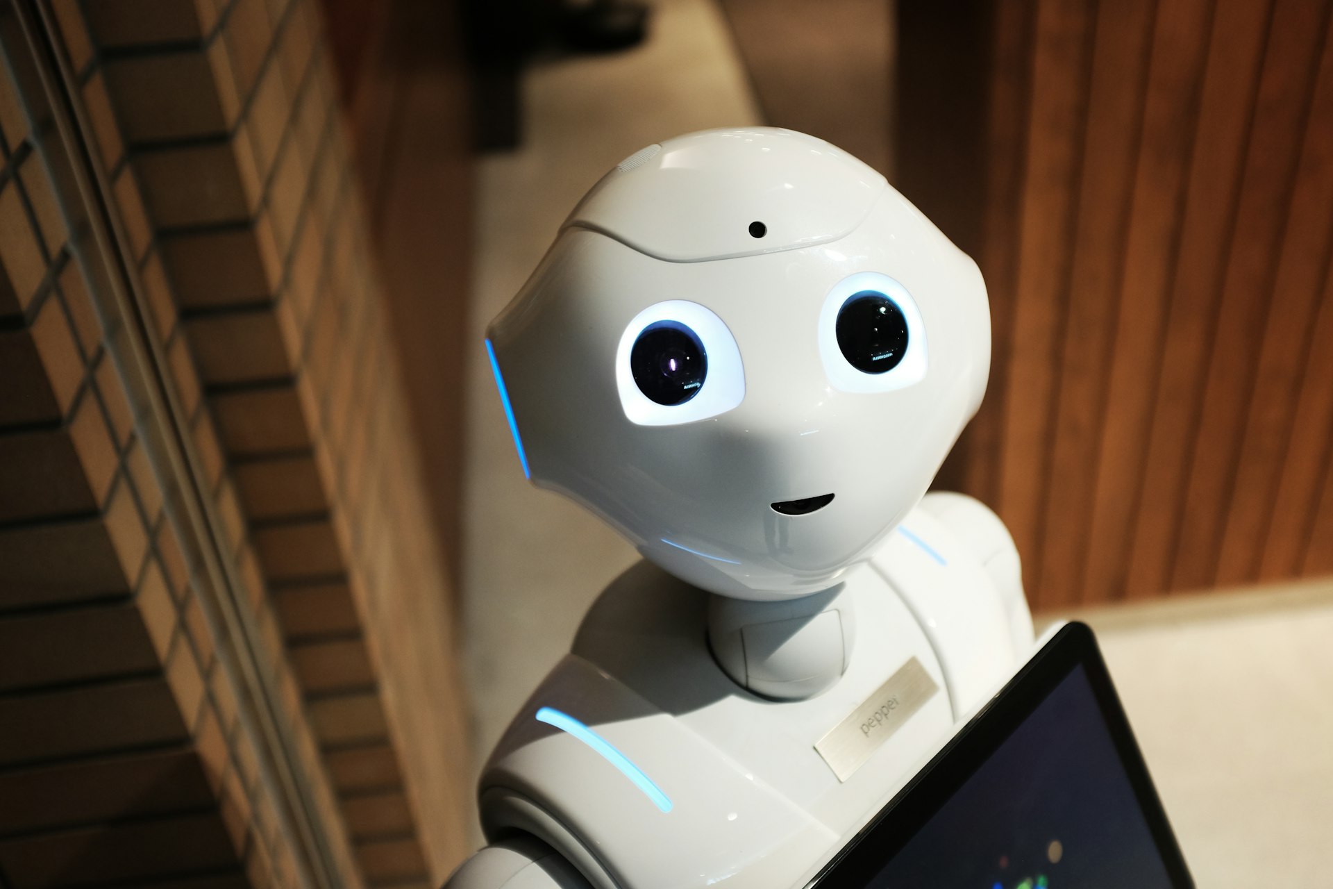 Pepper humanoid robot with blue LED joints in an indoor lobby