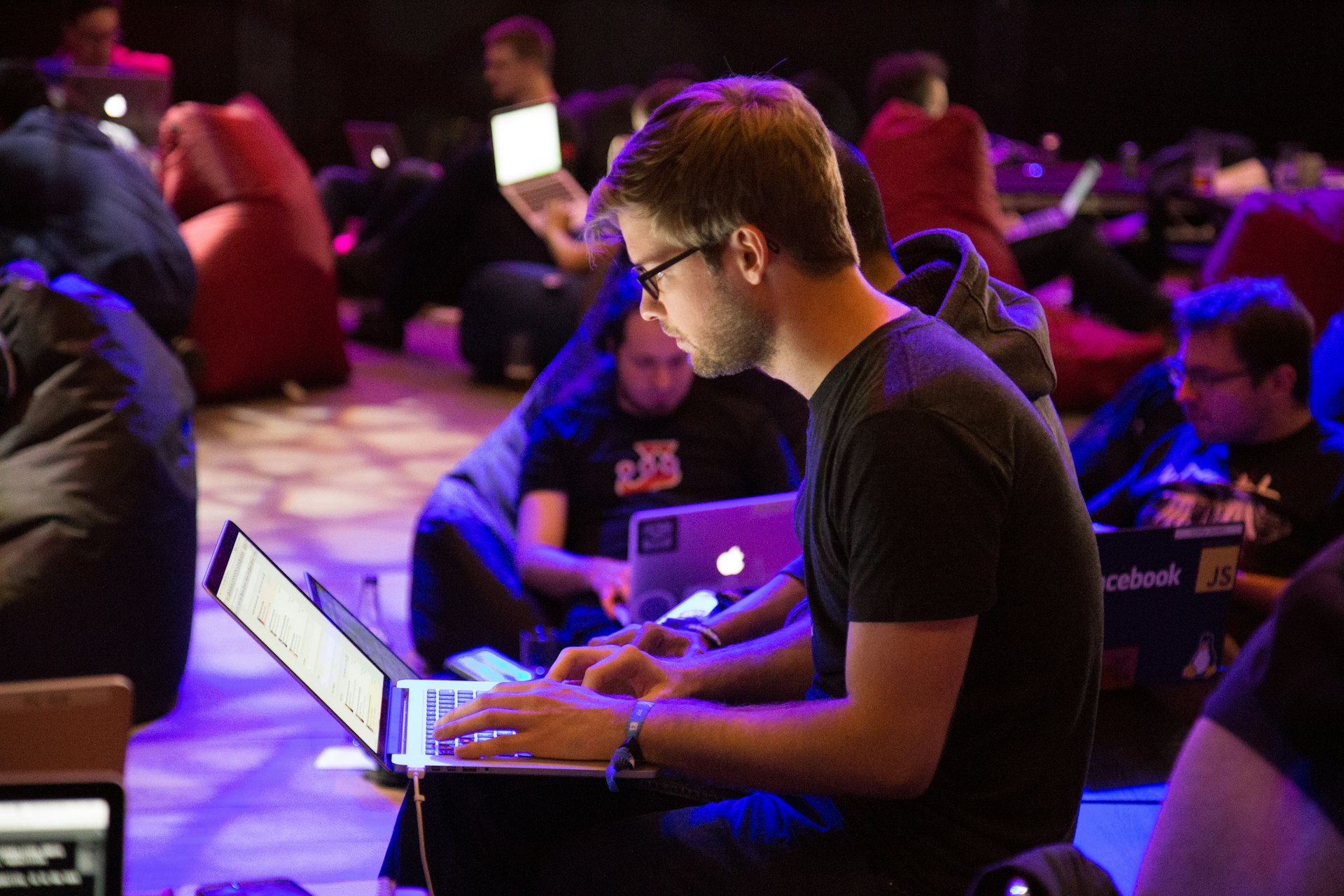 IT professionals working on laptops in a dim collaborative workspace